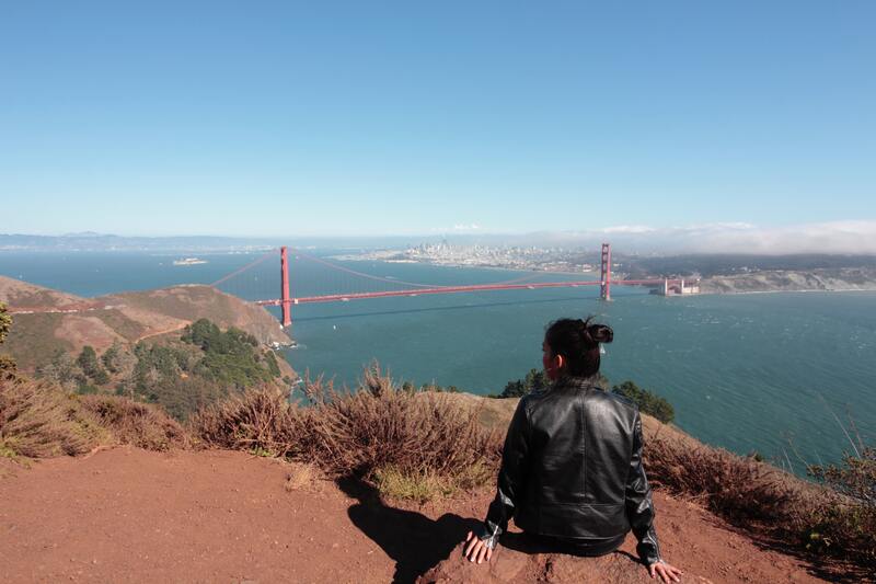Woman sitting on the rocks with a view to the Golden Gate Bridge