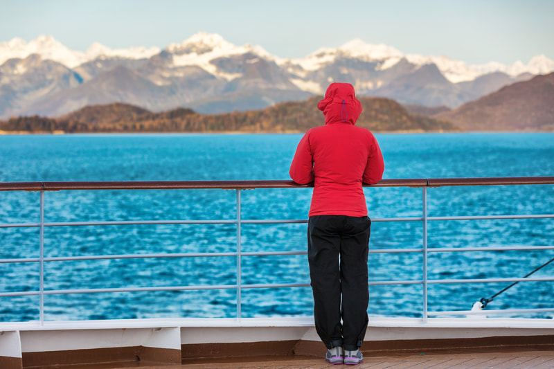 A woman looking at the mountains from a cruise. 